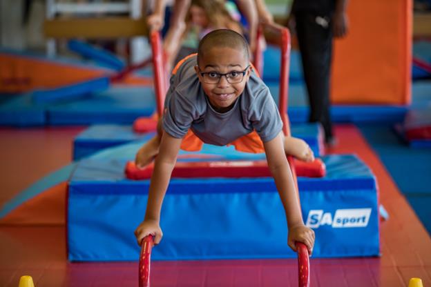 A boy on the climbing beams at the little gym